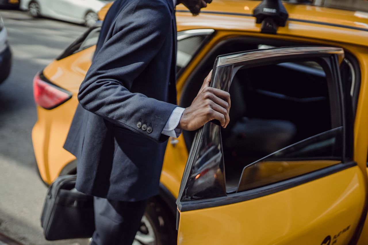 The Art of Drawing Readers In: Your attractive post title goes here A businessman in a suit opens the door to a yellow taxi on a city street during the day.