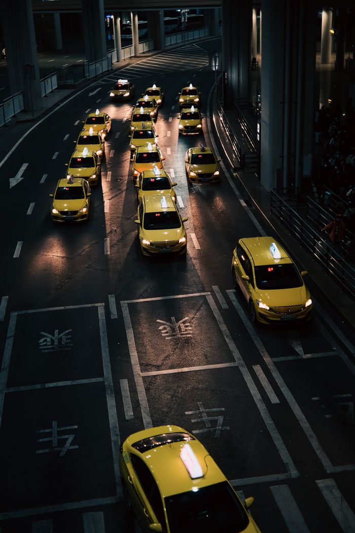 contact-img High angle view of lined yellow taxis on urban street during nighttime.