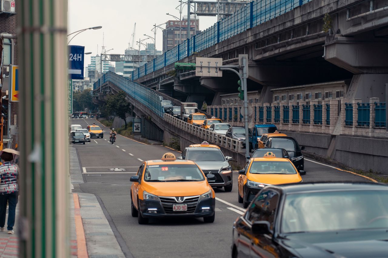about-02 Yellow taxis and vehicles navigating an urban street under an overpass.