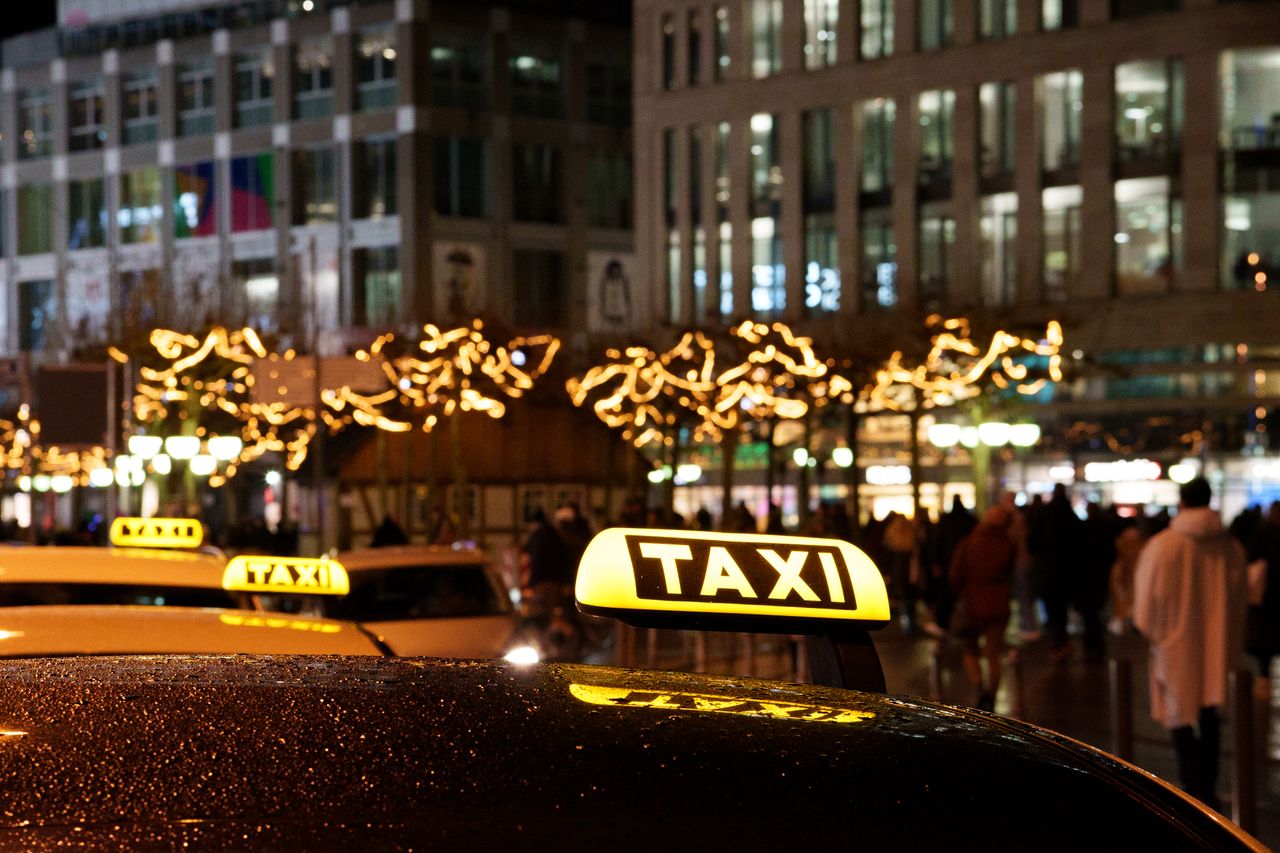 services-04 A vibrant city scene at night featuring taxis with illuminated signs and festive decorations.