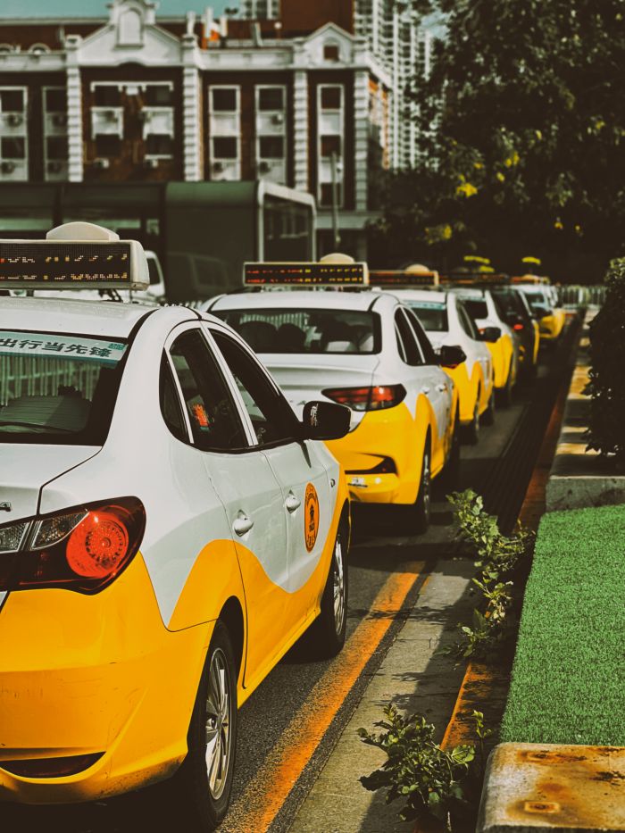 gallery-4 A row of yellow taxi cabs waits on a city street, providing urban transportation.