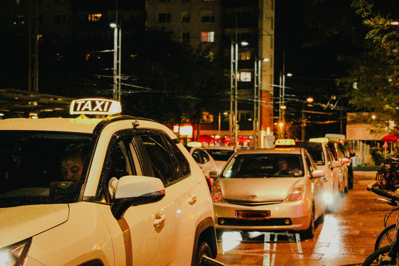 services-01 Taxis lined up under streetlights in Salzburg, Austria, captured at night.