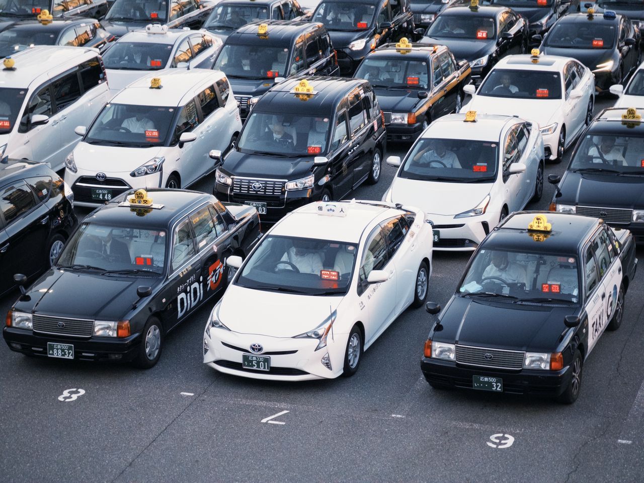ours-journey Taxis lined up in a parking lot, showcasing urban transportation in Japan.