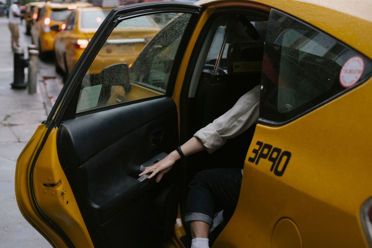our-experience Anonymous passenger closing door of cab parked on roadside with blurred cars on background in rush hour on street in city